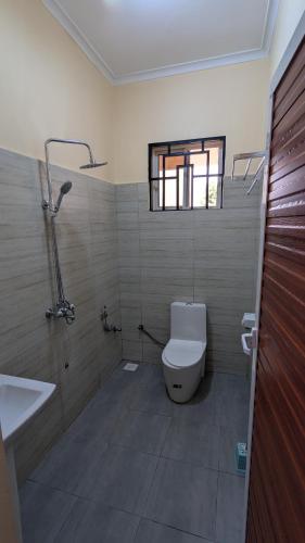 a bathroom with a toilet and a sink and a window at The Serene Maskani in Moshi