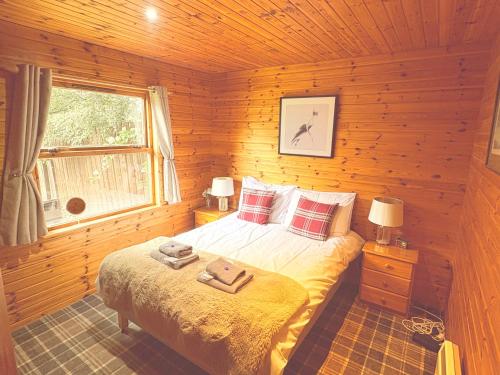 a bedroom with a bed in a log cabin at Braemar Lodge Cabins in Braemar