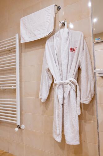 a white robe hanging on a wall in a bathroom at Hotel Melnik Хотел Мелник in Melnik