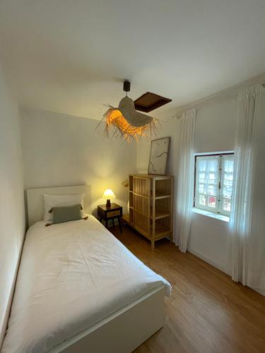 a bedroom with a white bed and a window at Casa dos Pintos in Paredes de Coura