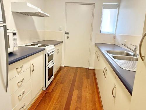 a kitchen with a sink and a stove at Cosy Ground Floor Walk to Adelaide Oval, City, Zoo & More in Adelaide