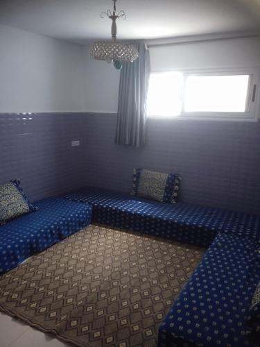 a room with two blue beds and a window at Tamraght banana house in Agadir