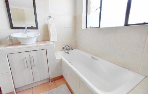 a bathroom with a sink and a bath tub and a mirror at Shallow Pig Cottage in Parys