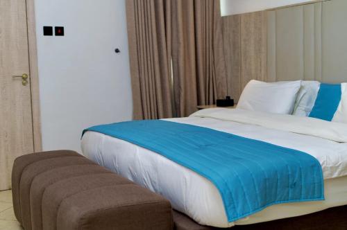 a bedroom with a large bed with a blue blanket at Tipson Apartments in Bamgbose