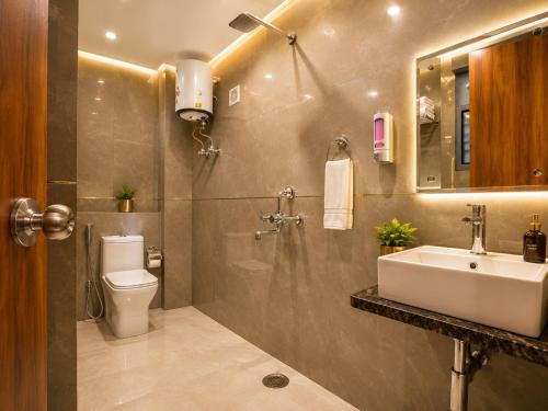 a bathroom with a sink and a toilet and a mirror at Hotel Grand Villa Suites Near Delhi International, IGI Airport in New Delhi