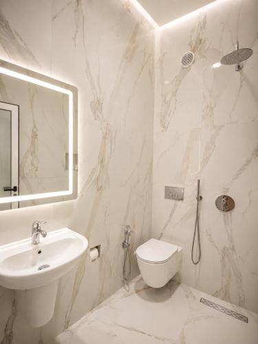a white bathroom with a sink and a toilet at Hotel Aleksandrus Jardin in Durrës