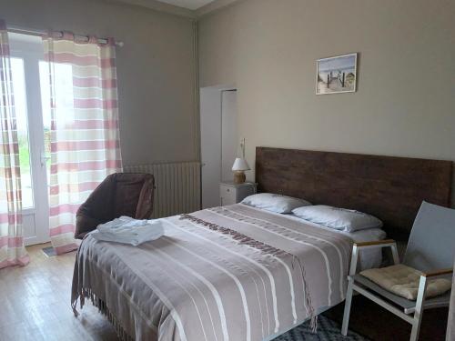 a bedroom with a large bed and a chair at La Costonnerie in Leigné-sur-Usseau