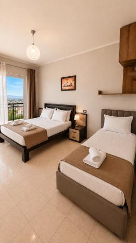 two beds in a large room with a window at Hotel Aleksandrus Jardin in Durrës