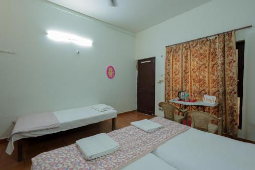 a room with two beds and a table with a table at Omji Ashram - Maa Anandmayi in Vrindāvan