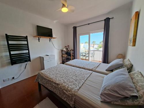 a bedroom with a bed and a tv and a window at Casa Svancy in Lagoa