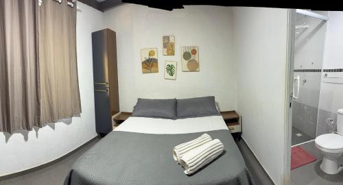 a small bedroom with a bed and a toilet at Kundalini Buzios in Búzios