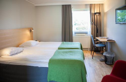 a bedroom with a bed with a green blanket on it at Allégården Kastlösa Hotell in Kastlösa