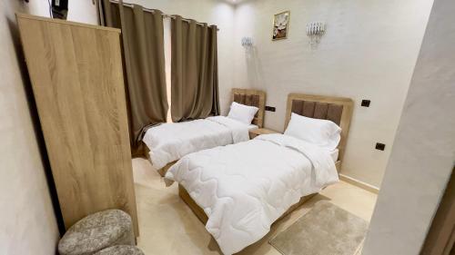 two beds in a room with white sheets at Hotel Almou in Ouarzazate