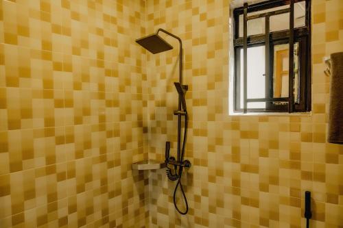 a shower in a yellow tiled bathroom with a window at Sabyinyo Crest in Cyuve