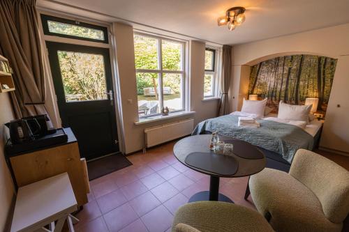 a hotel room with a bed and a table and chairs at Bed & Bos de 14 Sterren in Den Burg