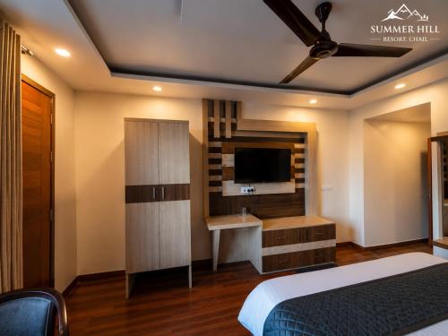 a bedroom with a bed and a tv and a desk at Summer Hill Resort in Chail