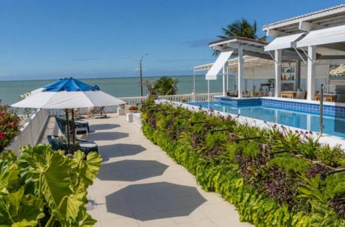 a swimming pool with an umbrella next to the ocean at SERHS Beach Hotel in Natal