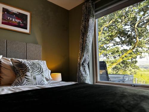 a bedroom with a bed and a large window at Cadderlie Cabin - Luxury Woodland Escape with Hot Tub Near Oban in Oban
