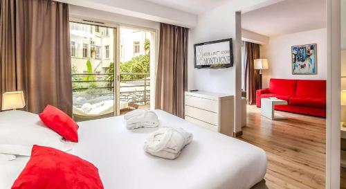 a hotel room with two beds and a red couch at Hôtel Montaigne & Spa - Cannes Centre in Cannes