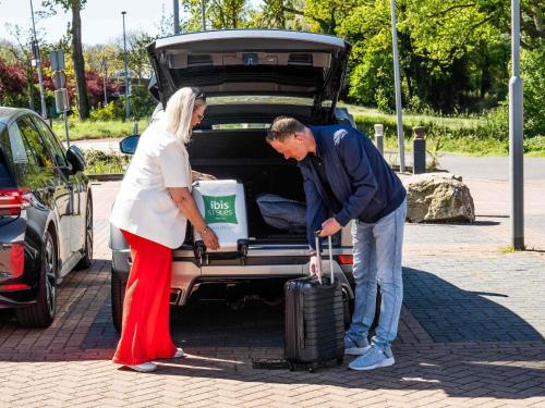 a man and woman putting their luggage into the trunk of a car at ibis Styles Haarlem City in Haarlem