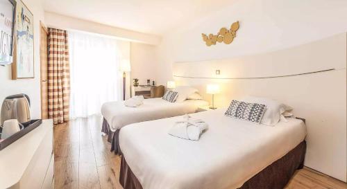 a hotel room with two beds and a television at Hôtel Montaigne & Spa - Cannes Centre in Cannes