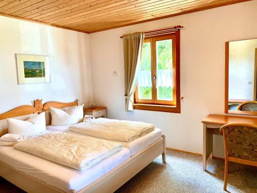 a bedroom with two beds and a desk and a window at Ferienhotel Mühlleithen in Klingenthal