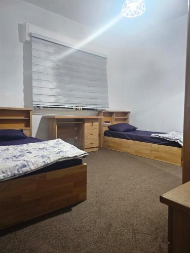 a bedroom with two beds and a desk and a window at الجبيهه شفابدران شقة مفروشة in Amman