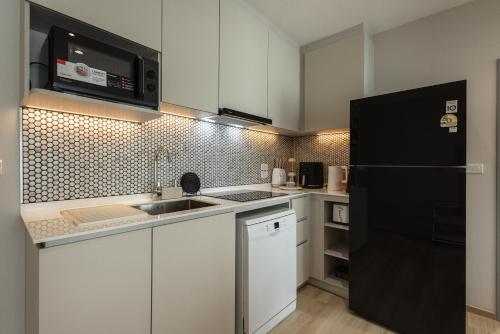 a kitchen with white cabinets and a black refrigerator at A417-60m2-2bedroom Serenity 66935B2I976 in Nai Yang Beach