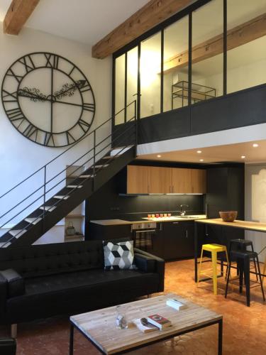 a living room with a black couch and a clock at Les Suites du Cours & Spa in Aix-en-Provence