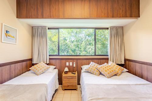 two beds in a room with a window at Guarajuba, apart 1/4 próximo à praia in Guarajuba