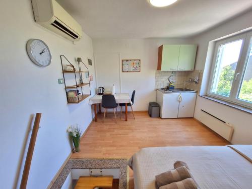a room with a kitchen and a table with a clock at Apartment Carolina - Hillside Stay, Steps from the Sea in Portorož