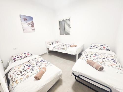 three beds in a room with white walls at המקום של אסי - Assi's place in Oshrat