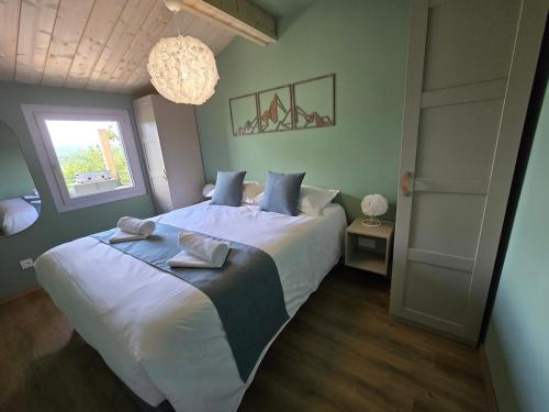 a bedroom with a large bed with two towels on it at Les Reflets Bleus in Maisod
