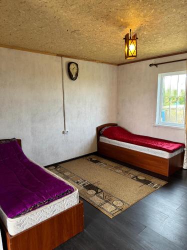 a bedroom with two beds and a clock on the wall at Guest house Begai Ene in Tong
