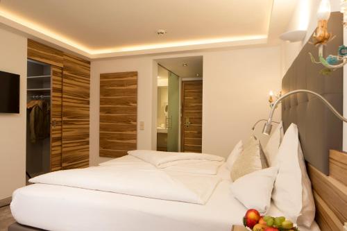 a bedroom with a white bed and a mirror at Hotel Neuhaus in Saalbach Hinterglemm