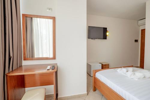 a hotel room with a bed and a desk and a television at Hotel Boutique Vioalv in Sarandë
