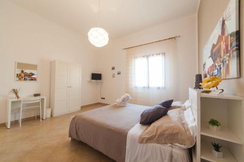 a white bedroom with a bed and a desk at B&B Bianco Sale Trapani in Rilievo