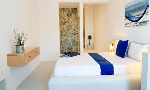 - une chambre avec un grand lit blanc aux accents bleus dans l'établissement Astropalia Luxury Studios, à Astypalée