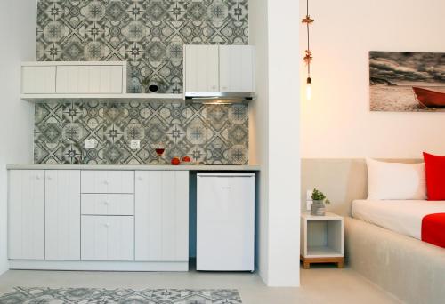 アスティパレア・タウンにあるAstropalia Luxury Studiosの白いキャビネット付きのキッチン、ベッド1台が備わる客室です。