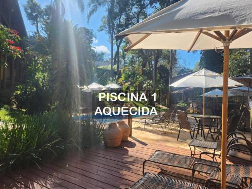 a wooden deck with an umbrella and chairs and tables at Pousada do Rodrigo in Macacos