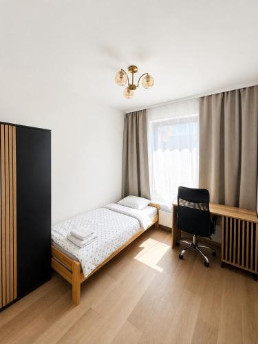 a bedroom with a bed and a desk and a chair at Justinrent PALATIUM 31 in Legnica