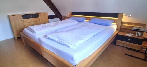 a large bed with white sheets and blue pillows at Milchhäusle in Söllingen