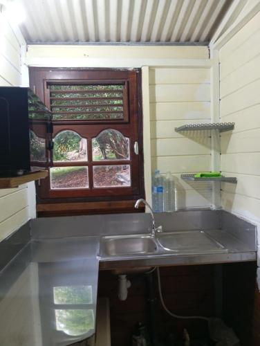 a kitchen with a sink and a window at cabane dans le jardin in Morne-à-lʼEau