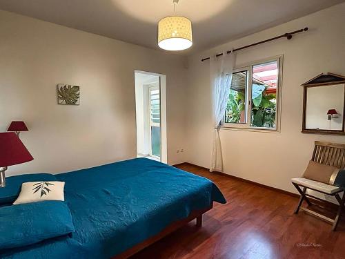 a bedroom with a blue bed and a window at Ty Lodge Réunion, Piscine, Spa, Vue Océan, Jardin, entre Saint-Pierre et volcan in Le Tampon