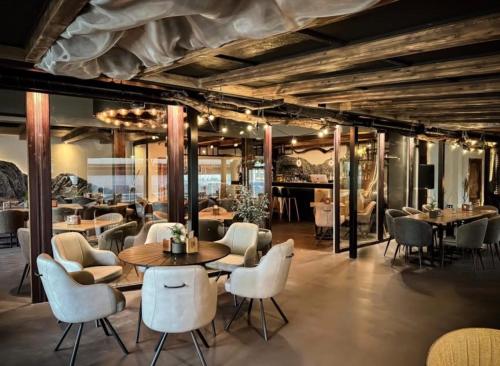 a restaurant with white chairs and tables and tablespaces at Vanaga Ligzda in Baltezers