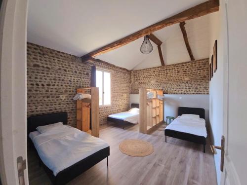 a bedroom with two beds and a brick wall at La parenthèse de Saint Esselin 2 in Larreule
