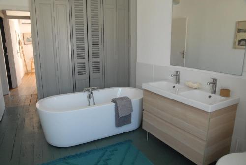 a white bathroom with a tub and two sinks at la colombe du marais in Courçon
