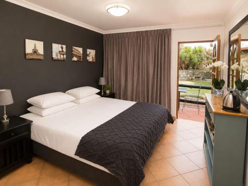 a bedroom with a large bed and a balcony at Anna Boeremeisie Guesthouse in Benoni