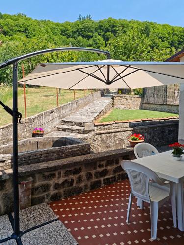 a patio with a table and chairs and an umbrella at Sosta FONTE DAVIDDI in Santa Fiora