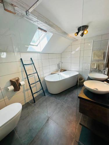 a bathroom with two sinks and a tub and two toilets at Maison de gesves in Gesves